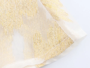 Gros plan sur maille blanc cassé avec texture dorée brillante et finitions d'ourlet
