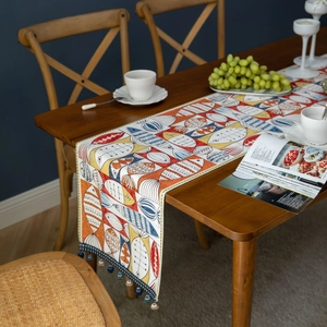 Colorful cartoon fish jacquard table runner with blue tassels on a rustic wooden table