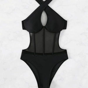Sultry black halter neck swimsuit with corset-style mesh patchwork on marble background