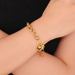 Detailed view of a gold heart charm bracelet on wrist with chunky chain links