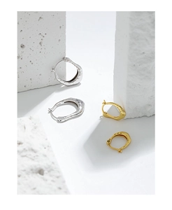 Detail of S925 sterling silver earrings with irregular lava texture on white stone