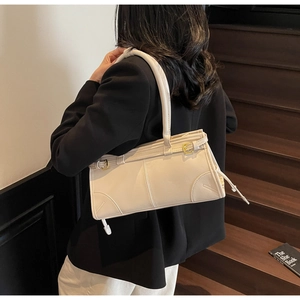 Close-up of cream PU leather shoulder bag with gold metal clasp on wooden stairs