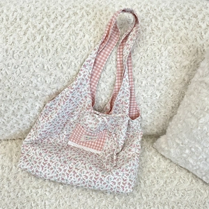 Detail of floral canvas tote bag showing lace trim and soft fabric texture on plush background