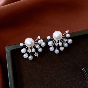 Macro shot of fan-shaped pearl earrings with cubic zirconia on a luxury black leather box