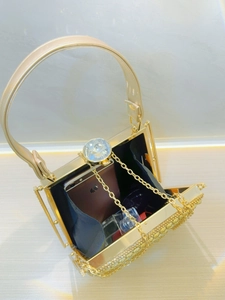 Macro detail of gold evening bag showing crystal clasp and space for a smartphone