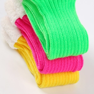 Close-up of three knitted leg warmers in green, pink, and yellow with plush fleece trim