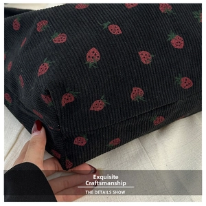 Detail of strawberry pattern and vertical texture on black corduroy shoulder bag fabric