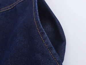 Detail eines dunkelblauen Denim-Sets mit gebogenen Taschenrändern und gelber Kontrastnaht