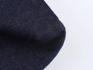 Texture dettagliata del tessuto denim blu scuro con cuciture precise sul bordo del capo