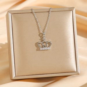 Titanium steel crown pendant necklace with cubic zirconia on champagne silk backdrop