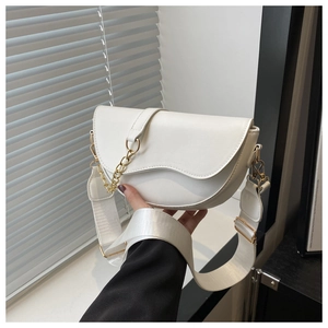 Close-up of white PU leather saddle bag with golden chain and wide shoulder strap