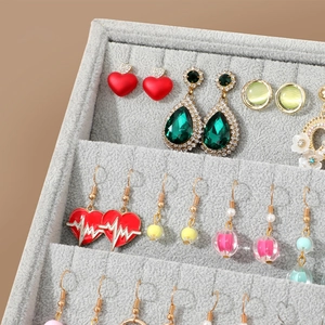 Grey velvet jewelry display tray with various earrings organized in neat parallel slots