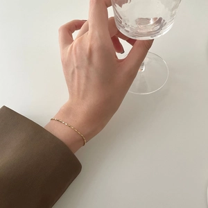 S925 sterling silver cube chain bracelet in gold finish worn with a brown blazer