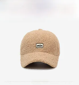Detailed close-up of beige Sherpa baseball cap featuring min letter embroidery patch