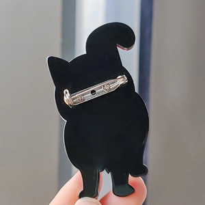 Detail of the safety pin closure on the back of a black acrylic cat-shaped brooch