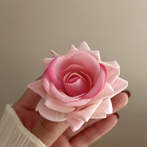Close-up of a pink faux silk rose hair clip showing delicate gradient fabric petals