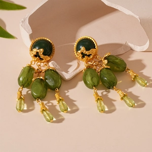 Détail de boucles d'oreilles rétro en résine goutte vert olive avec accents dorés