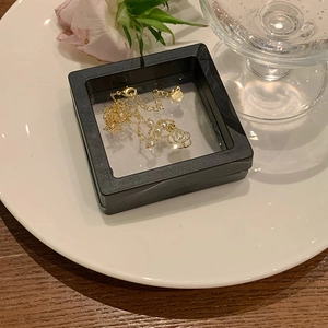 Detail of a gold pearl necklace inside a black jewelry box on a white decorative plate
