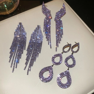 Macro shot of silver needle purple crystal fringe and wing drop earrings on leather