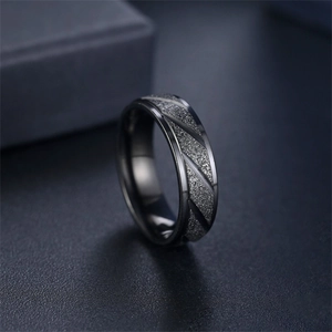 Dettaglio macro di un anello in acciaio al titanio nero satinato con motivi diagonali