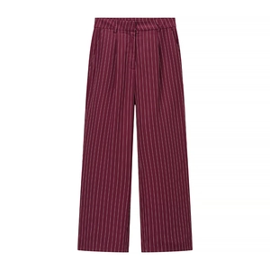 Detail view of burgundy pinstripe trousers featuring smart pleats and a wide-leg cut