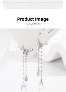 Detail of silver butterfly earrings with dangling chains and light blue teardrop pendants