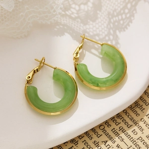 Detailed close-up of C-shaped 18k gold-plated earrings with green resin insets