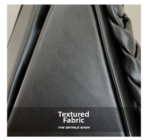 Close-up of black leather texture with woven twist handle detail on modern handbag