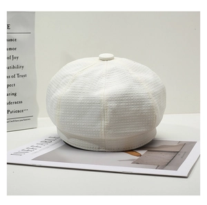 Detailed close-up of cream tweed newsboy cap texture and top decorative button