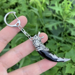 Handheld vintage wolf head keychain with a black wolf tooth pendant and silver ring