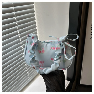 Detail of blue handheld bag featuring pink rose patterns and pleated fabric handle