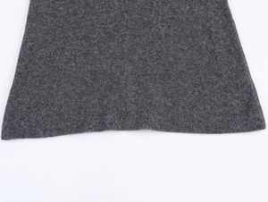 Detailed close-up of dark grey knitted fabric texture and hem on a white background