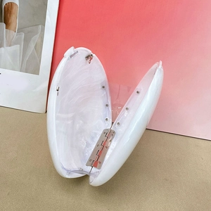 Detail view of acrylic clutch bag featuring white marble texture and metal hinges
