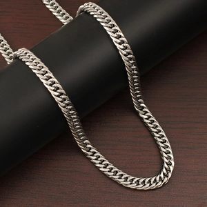 Macro shot of silver Cuban link necklace showing polished metal texture on wood