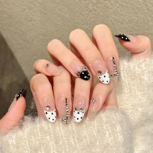 Unghie finte a mandorla chic con pois bianchi e neri e fiocchi 3D decorativi