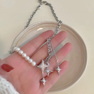 Detail of silver pearl necklace with chunky chain and three sparkling star pendants