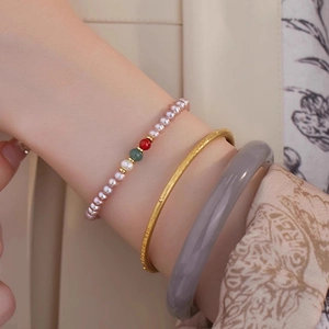 Close-up of stacked freshwater pearl bracelet with agate beads and a gold matte bangle