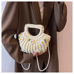 Detail of a handmade cream crochet shell bag with daisy decor and pearl strap