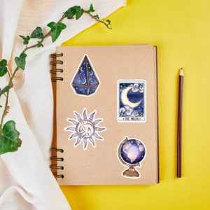 Flat lay of celestial magic stickers with sun and moon designs on a kraft notebook