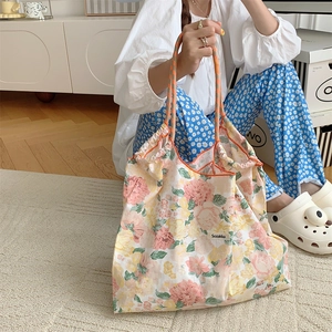 Detailed view of floral canvas tote bag with drawstring held by a model in a cozy setting