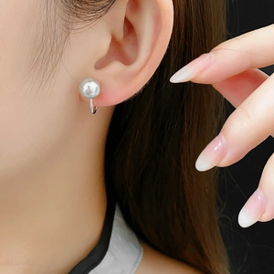 Elegant white pearl ear cuff with polished silver finish shown on a model's ear