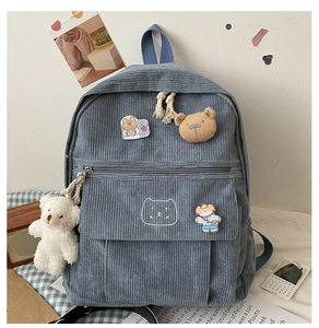 Detalle de mochila de pana azul con parche de oso y llavero de peluche para niñas