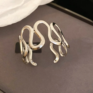 Detail shot of a silver wave-shaped cuff bracelet with a high-polished liquid metal finish