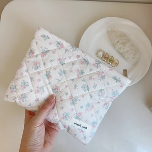 Detail of floral quilted cotton makeup bag with simple wish label and soft texture