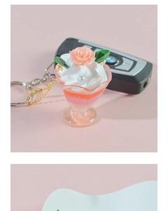 Close-up of artificial dessert keychain featuring pink cream, resin rose and gold chain