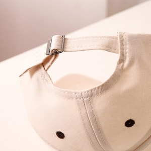 Detail of children's baseball cap with adjustable metal buckle and beige canvas fabric