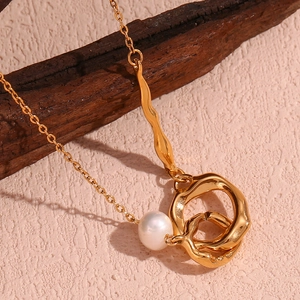 Détail du pendentif double boucle asymétrique plaqué or 18K avec perle blanche sur bois