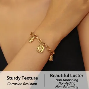 Detailed shot of 18K gold plated chain bracelet with owl, rose, and beetle charms on wrist