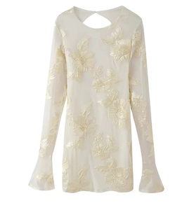 Detail of floral embroidery on cream dress with bell sleeves and hollow back design