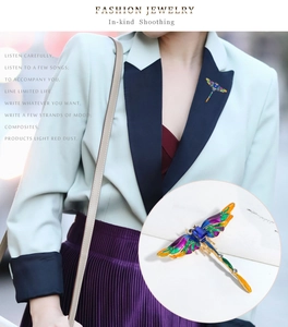 Close-up of enamel dragonfly brooch with colorful wings and blue gemstone inlay